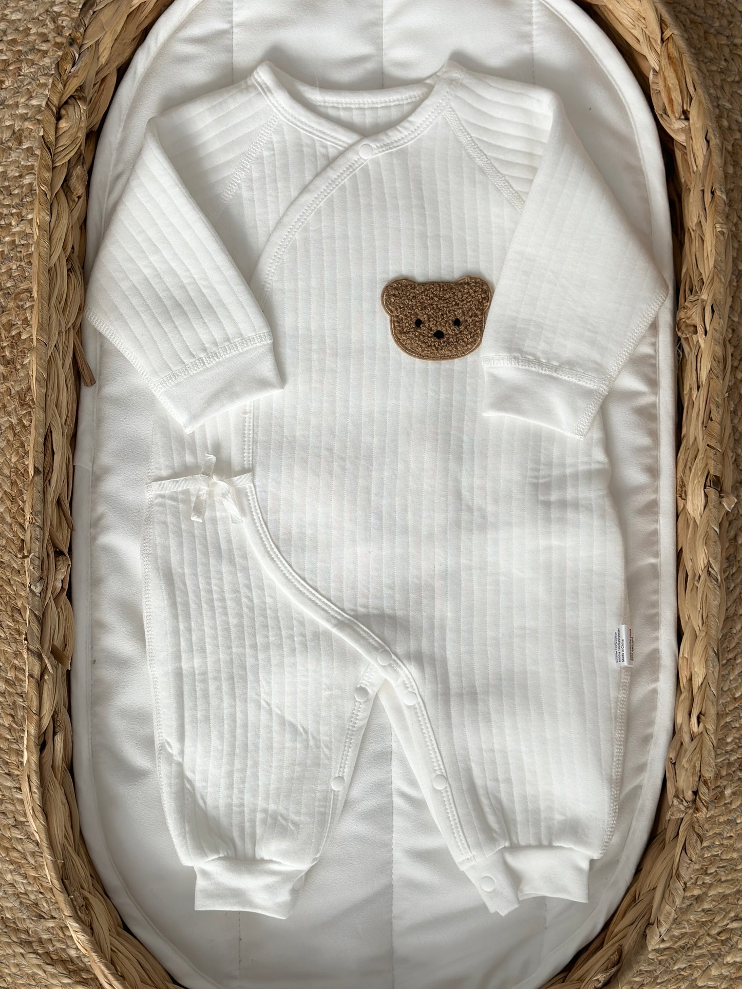 White baby romper crafted from soft bouclé fabric with a wrap design for snug comfort.